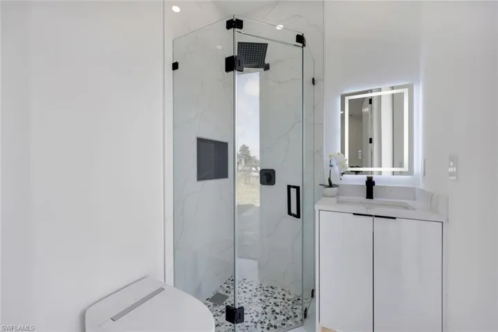 Bathroom featuring vanity, toilet, and a shower with door