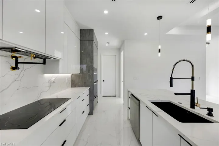 Kitchen featuring pendant lighting, light stone counters, and appliances with stainless steel finishes