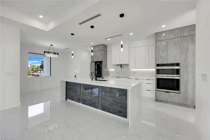 Kitchen featuring tasteful backsplash, pendant lighting, stainless steel double oven, a large island, and white cabinets