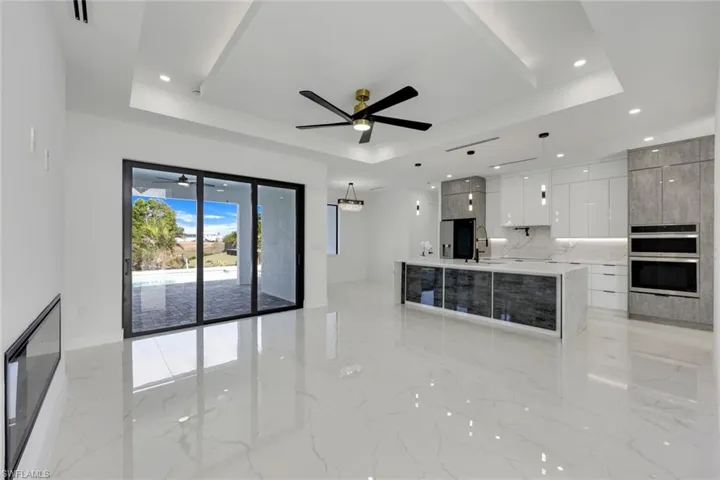 Kitchen featuring a large island, white cabinetry, a tray ceiling, and decorative light fixtures