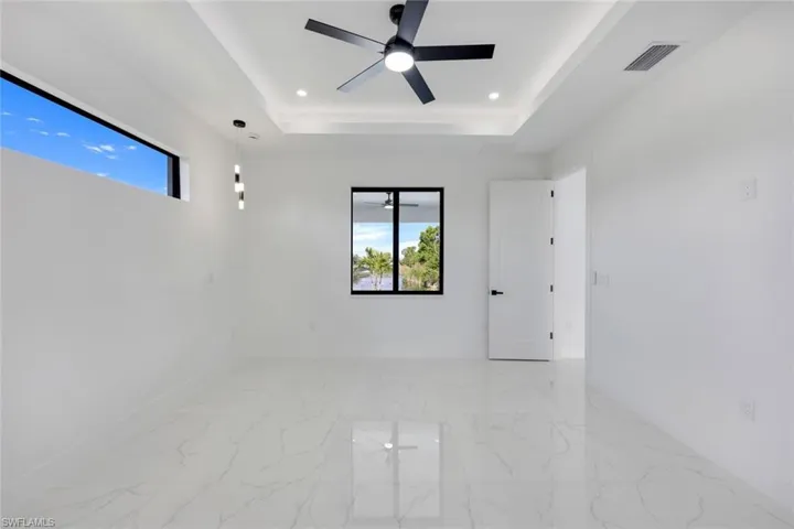 Unfurnished room featuring ceiling fan and a tray ceiling