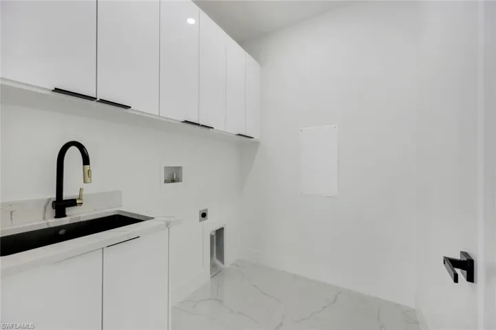Clothes washing area featuring cabinets, washer hookup, sink, and hookup for an electric dryer
