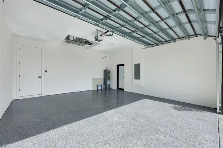 Garage with a garage door opener, electric panel, and water heater