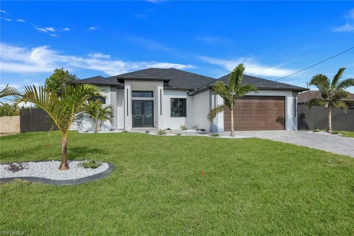 View of front of property with a garage and a front lawn