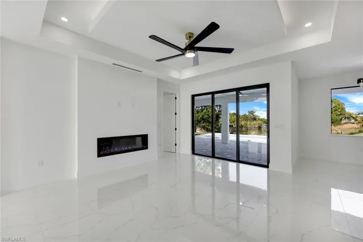 Unfurnished living room featuring ceiling fan and a tray ceiling