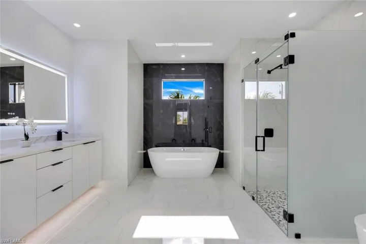 Bathroom featuring vanity and separate shower and tub
