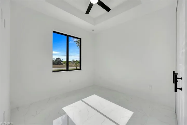 Spare room with ceiling fan and a tray ceiling