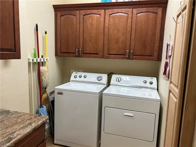 Laundry area featuring cabinets, granite countertop, built in ironing board, washing machine and dryer