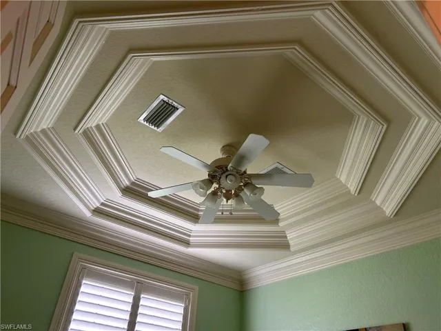 Bedroom 3 with fan, trayed ceiling and crown molding.