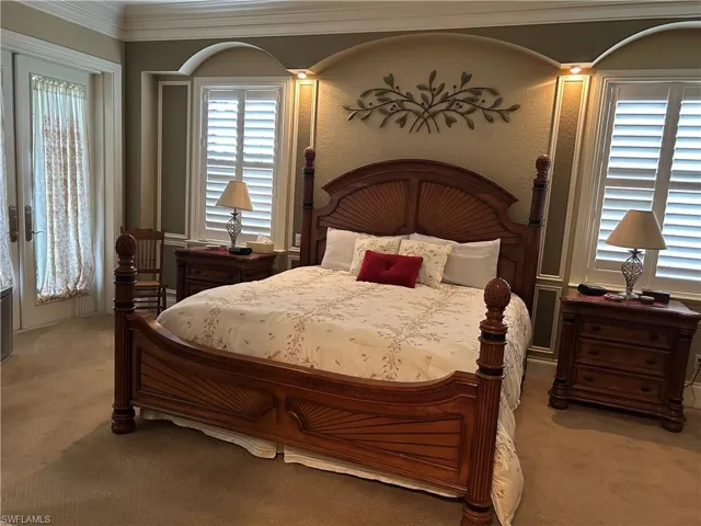 Master bedroom with plantation shuttered windows, French doors to pool area, ceiling fan, tray ceiling with crown molding.