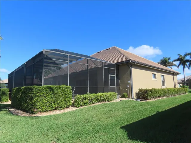 Rear view of house from right side featuring pool cage and lawn.