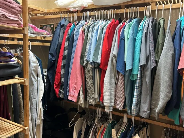 Partial View of walk-in closet with wood shelving, one on each side of hallway.