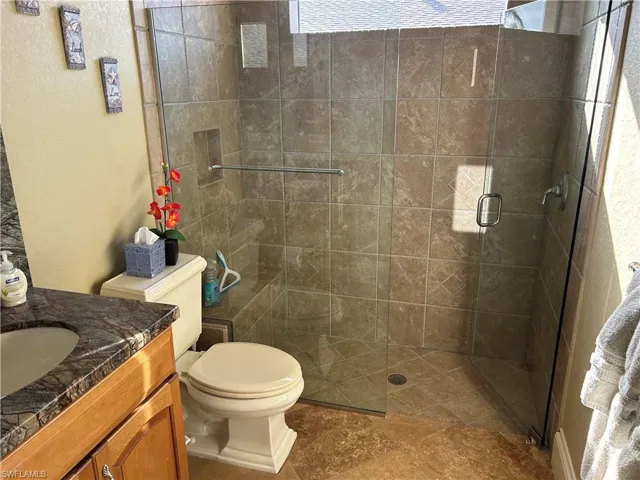 Bathroom 3 featuring wood vanity with granite top, toilet, walk in shower, and a healthy amount of sunlight.