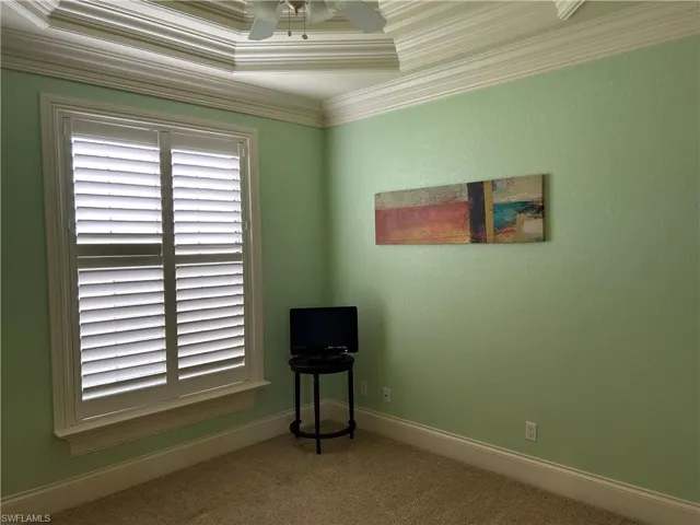 Bedroom 3 with ceiling fan, plantation shutters, and tray ceiling with crown molding.