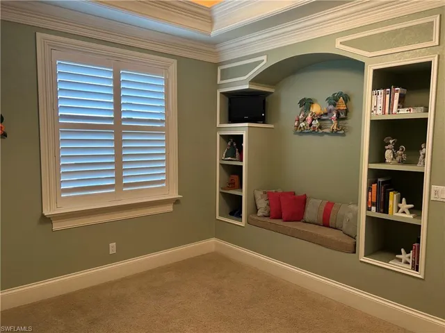 Bedroom 4 with built-in shelving and sitting bench, plantation shutters, trayed ceiling with crown molding.