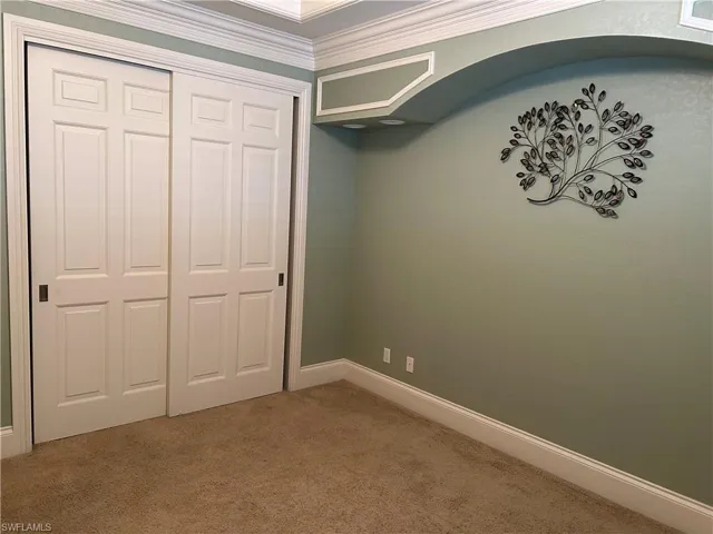 Bedroom 4 with built-in shelving and sitting bench, closet, plantation shutters, trayed ceiling with crown molding.