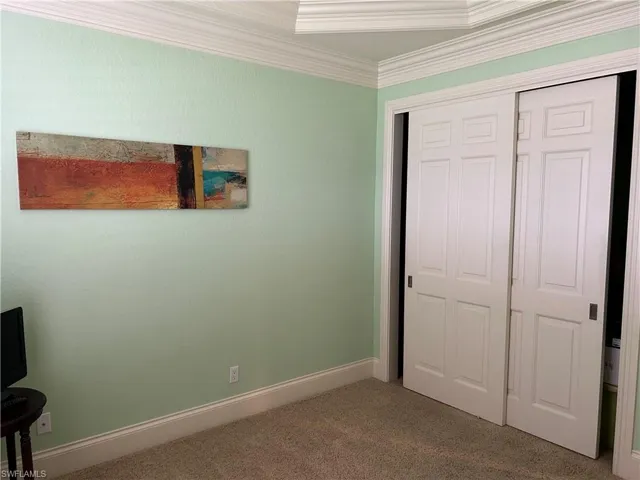 Bedroom 3 with ceiling fan, plantation shutters, doors to closet and tray ceiling with crown molding.
