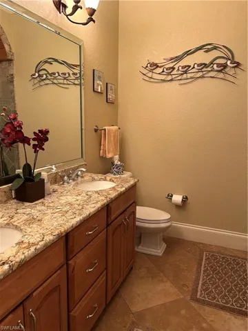 Bathroom 2 featuring double sink vanity with wood cabinets and granite countertop, walk-in shower and toilet.