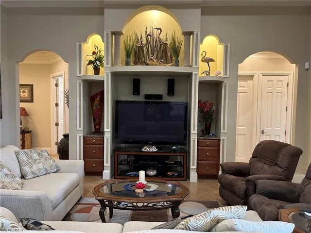 Tiled living room featuring built in features and ornamental molding