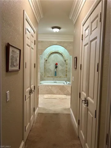 Hallway from Master BR to Master BA with closet entrances on both sides and crown molding.