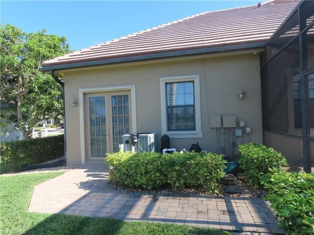 Back of house featuring A/C unit, a paver walkway, and French doors from back of 3rd garage space.
