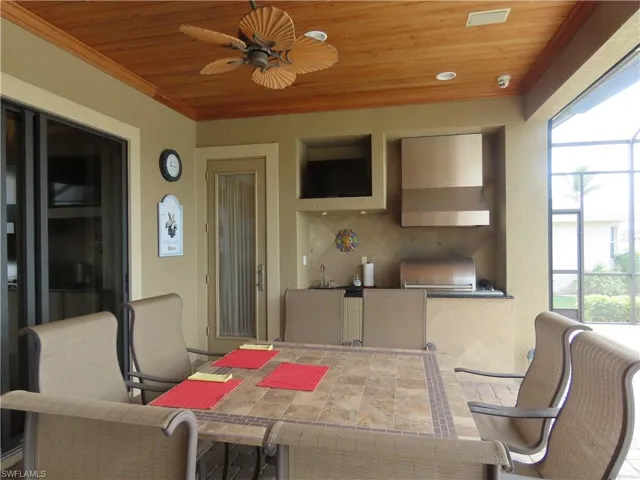 Lanai looking at outdoor Kitchen with sink and vented grill including a ceiling fan and wood ceiling.