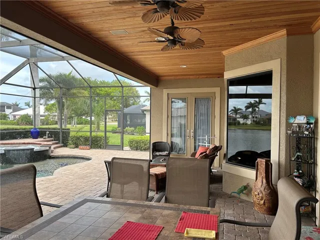 Lanai with nook glass enclosure, French doors, a pool and lake view, ceiling fan, and dining and seating area.
