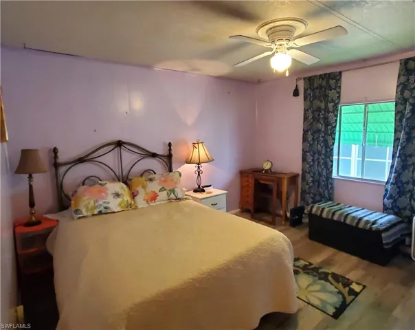 Guest bedroom with laminate floor and ceiling fan.