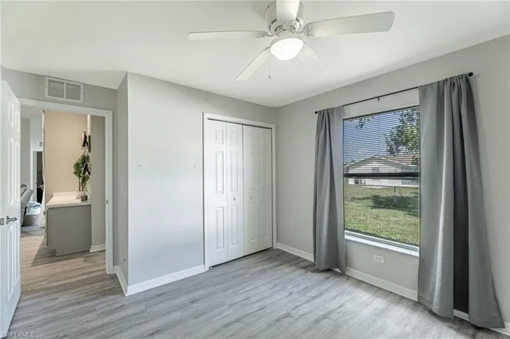Unfurnished bedroom featuring a closet, ceiling fan, multiple windows, and light wood-type flooring