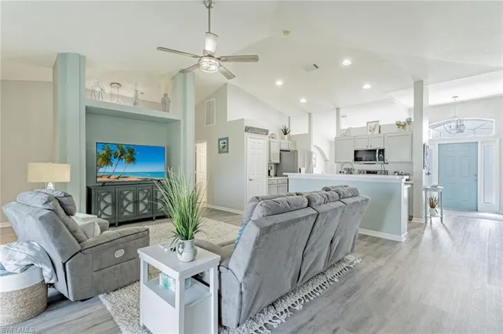 Living room with high vaulted ceiling, light wood-type flooring, and ceiling fan
