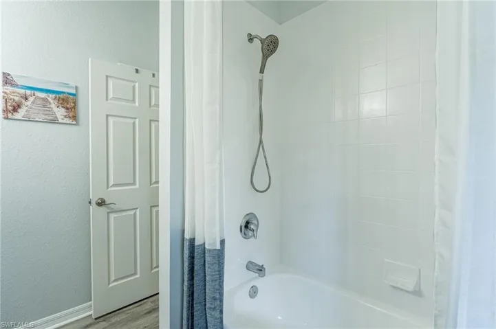 Bathroom featuring hardwood / wood-style flooring and shower / bath combination with curtain