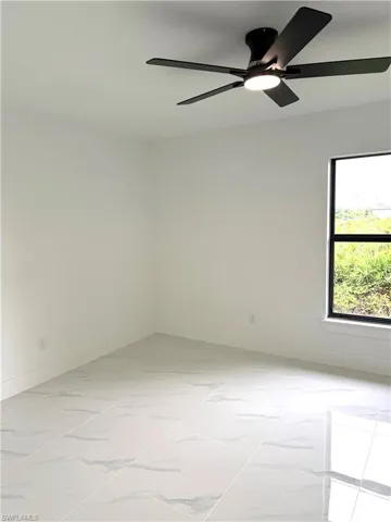 Empty room featuring light marble finish flooring and ceiling fan