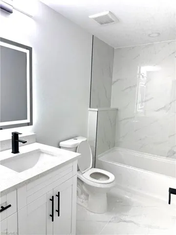 Bathroom featuring vanity, a combined bath / shower with marble appearance, and marble look tiles