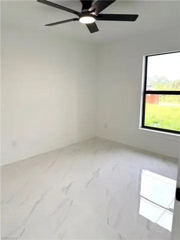 Empty room with a ceiling fan and light marble finish flooring