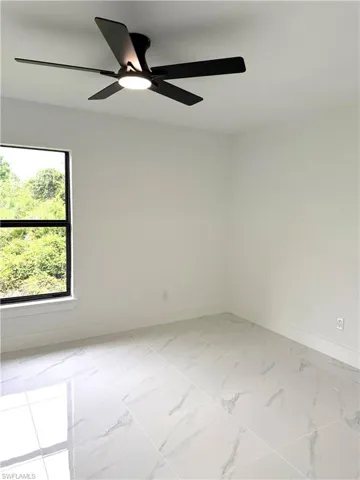 Spare room featuring light marble finish flooring and ceiling fan