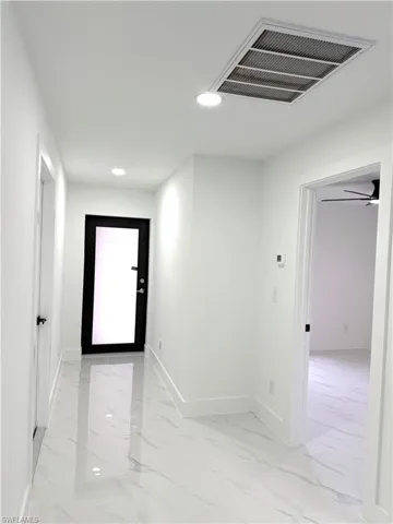 Hall with recessed lighting and light marble finish floors