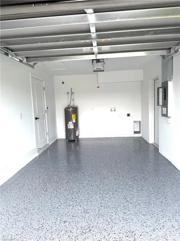 Garage featuring water heater, electric panel, and a garage door opener