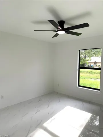 Empty room with light marble finish floors and ceiling fan
