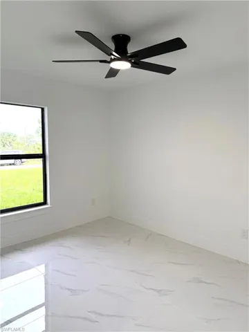 Unfurnished room featuring light marble finish flooring and ceiling fan