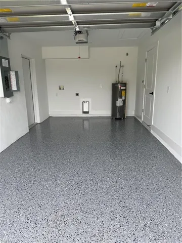 Garage with electric panel, water heater, and a garage door opener