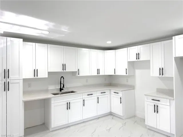 Kitchen with white cabinetry, light marble finish floors, light stone countertops, and recessed lighting