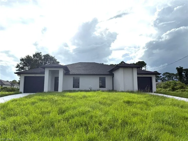 Prairie-style home with a garage, stucco siding, and driveway