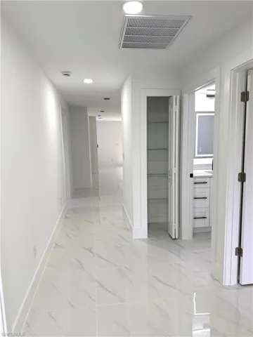 Corridor featuring light marble finish flooring and recessed lighting