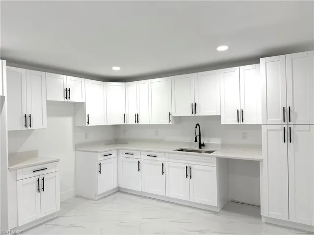 Kitchen with white cabinetry, light marble finish flooring, light stone countertops, and recessed lighting