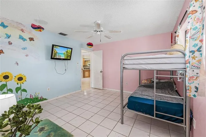 Unfurnished bedroom with light tile patterned flooring, a textured ceiling, and ceiling fan