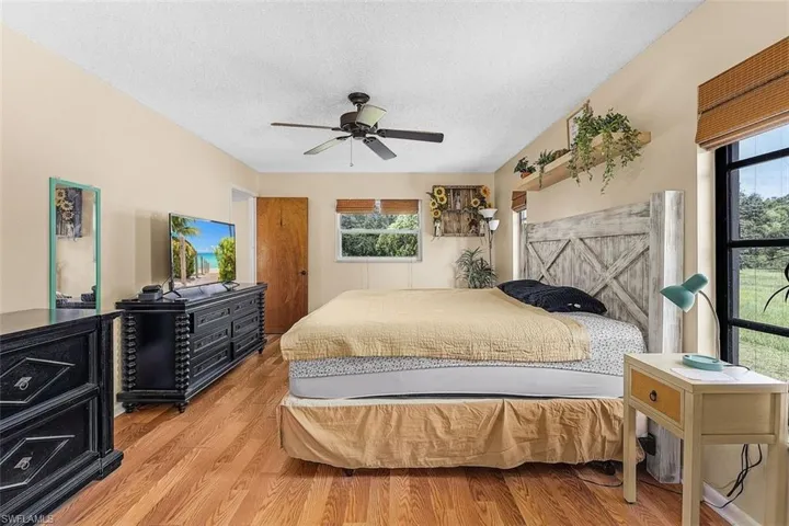 Bedroom featuring a textured ceiling, multiple windows, wood-type flooring, and ceiling fan