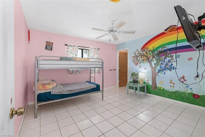 Tiled bedroom featuring a textured ceiling and ceiling fan