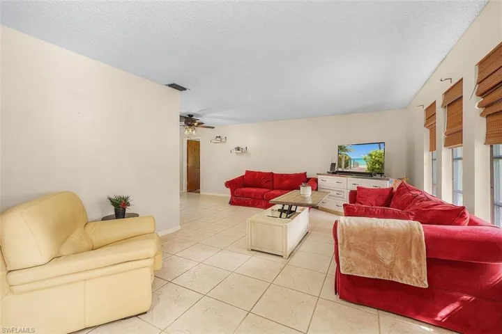 Living room featuring light tile patterned flooring, a textured ceiling, and ceiling fan