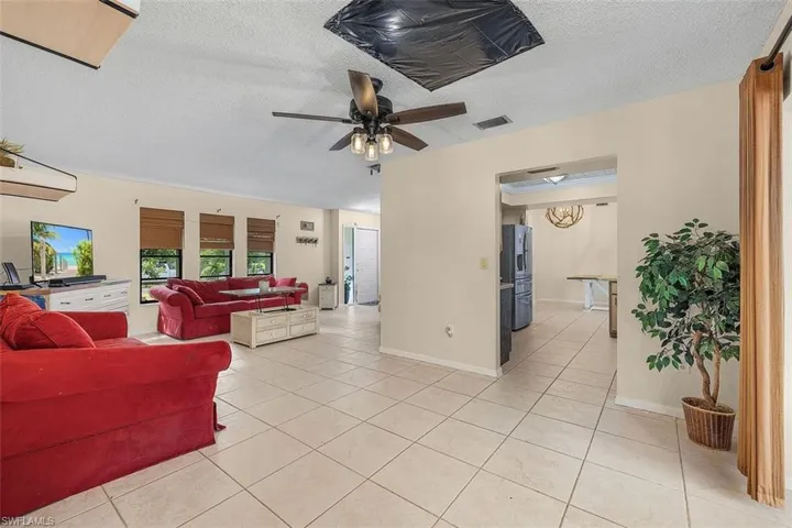 Living room with a textured ceiling, light tile patterned floors, and ceiling fan