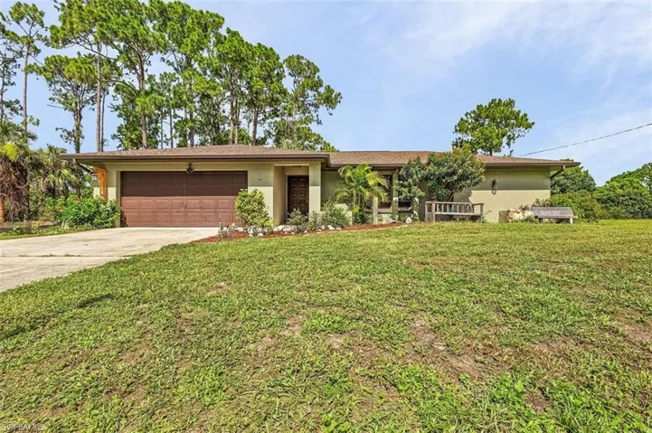 Ranch-style home featuring a garage and a front lawn
